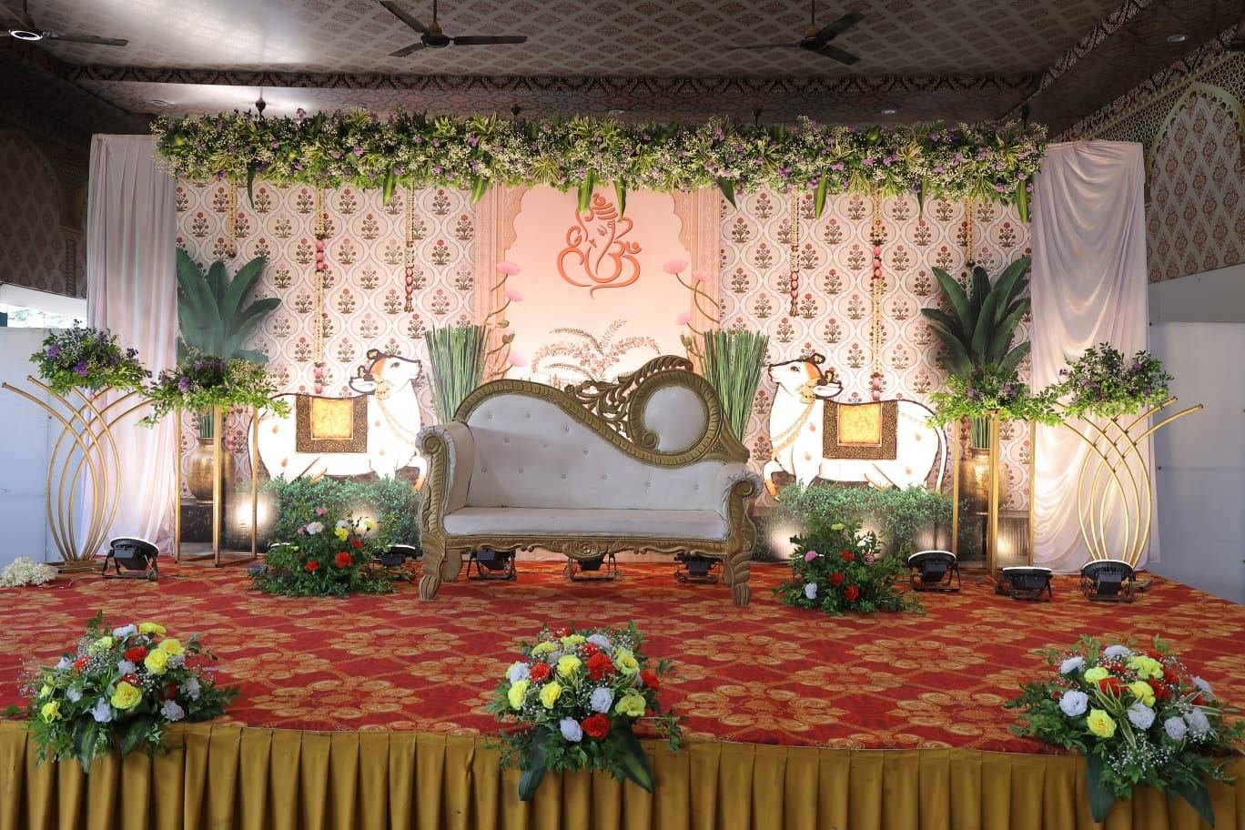 Elegant wedding reception stage with Ganesh motif backdrop and floral top border