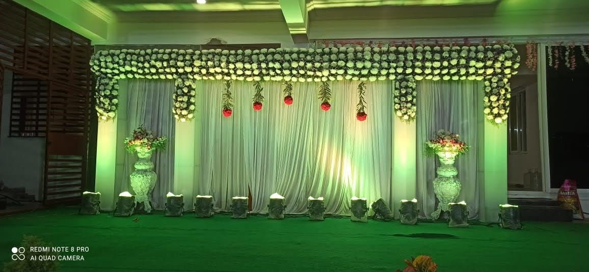 Green and white floral wedding stage with hanging accents